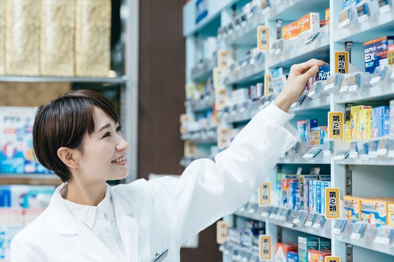棚の薬を手に取る女性スタッフ